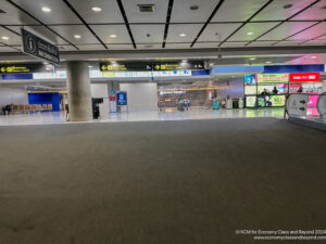 an empty airport with signs and people walking