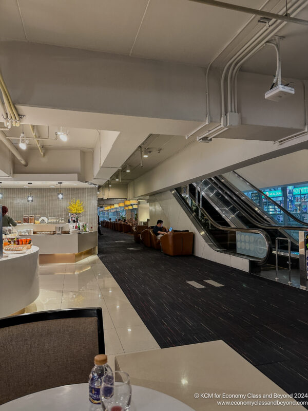 a room with escalators and people sitting in chairs