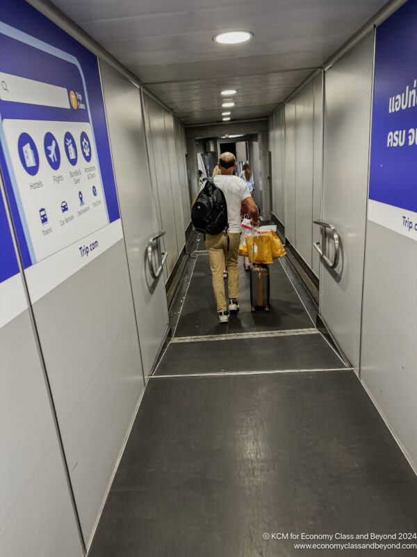 a man walking down a hallway with luggage