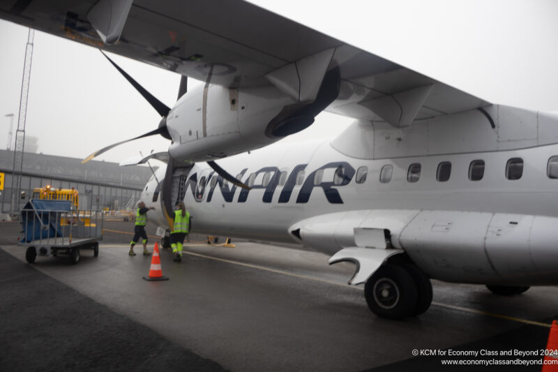 a plane with a propeller and people walking around