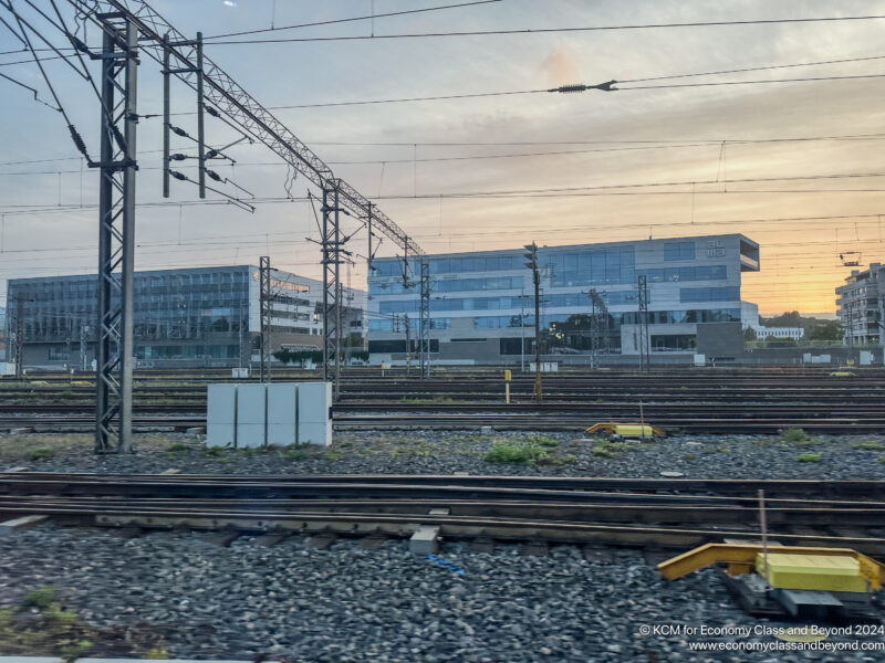 train tracks with power lines and buildings in the background