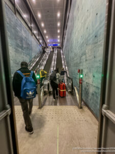 people walking down an escalator with luggage