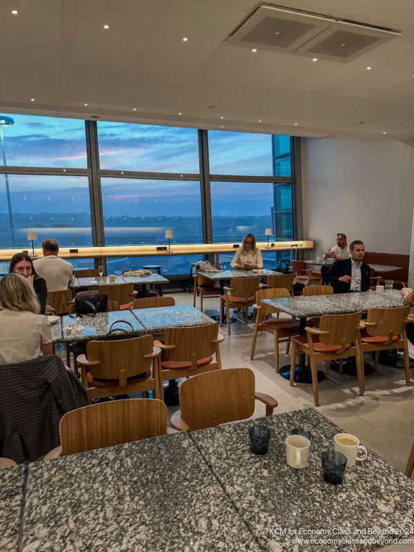 a group of people sitting at tables in a room with large windows