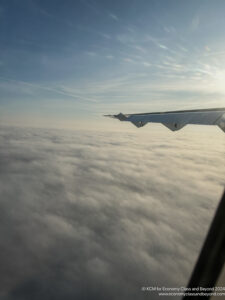 an wing of an airplane above clouds