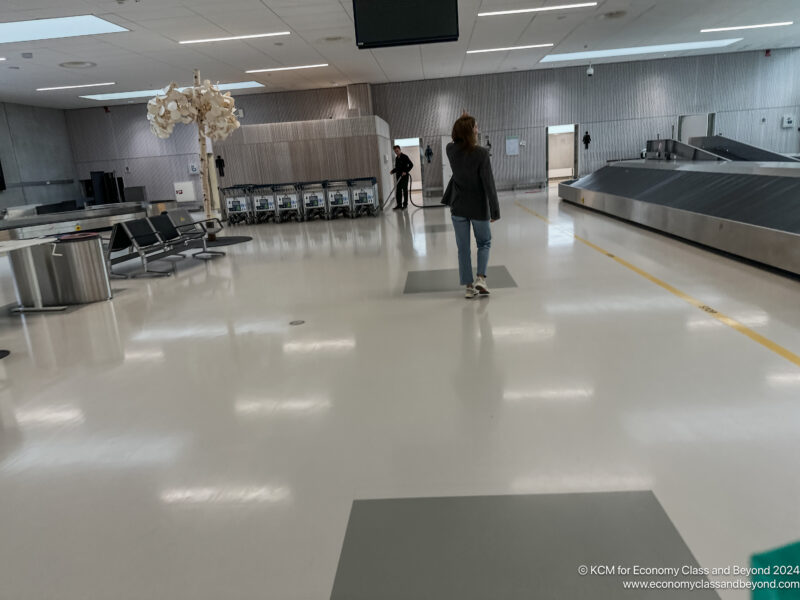 a woman walking in a large room with luggage conveyor belts