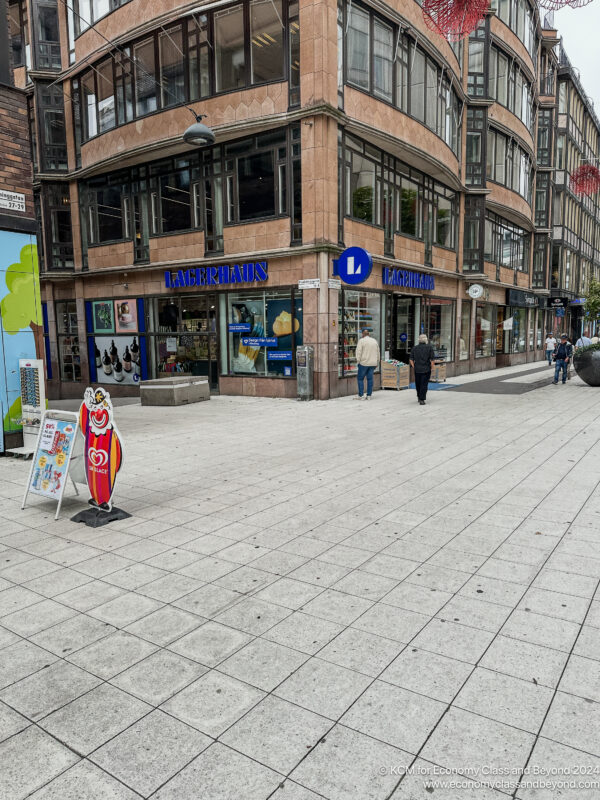 a sidewalk with people walking and a building