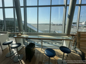 a table with stools and luggage in a room with large windows