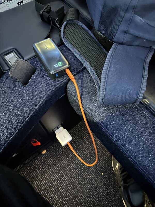 a black device with an orange cord attached to a blue seat