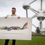 a man holding a poster in front of a large metal structure