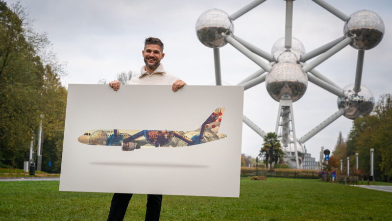 a man holding a poster in front of a large metal structure