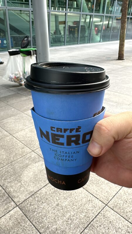 a hand holding a blue cup with a black lid