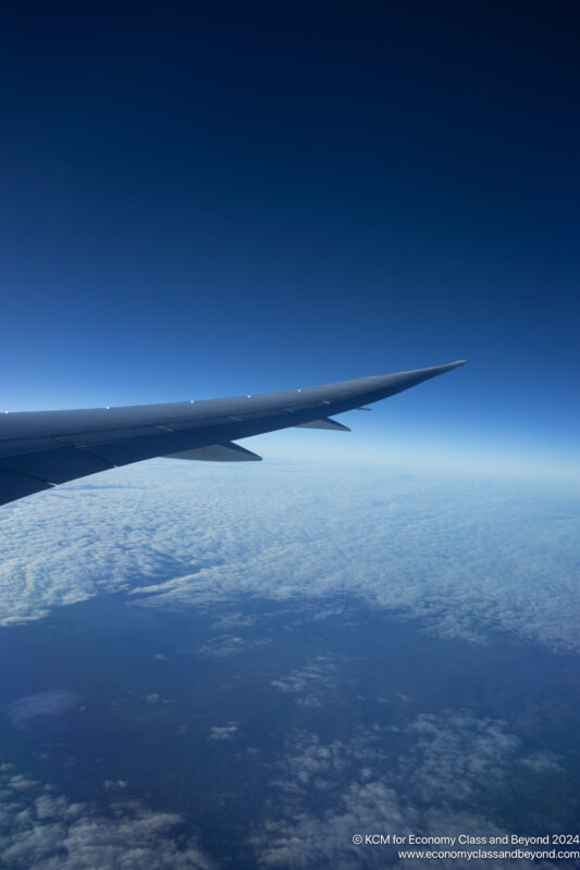 an wing of an airplane above clouds