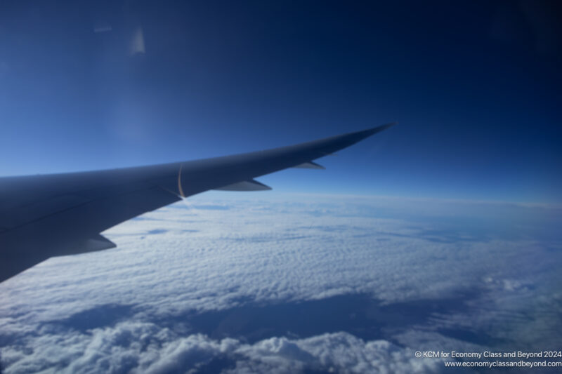 an wing of an airplane above the clouds