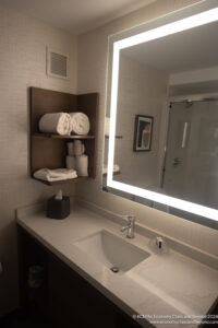 a bathroom with a mirror and a shelf with towels