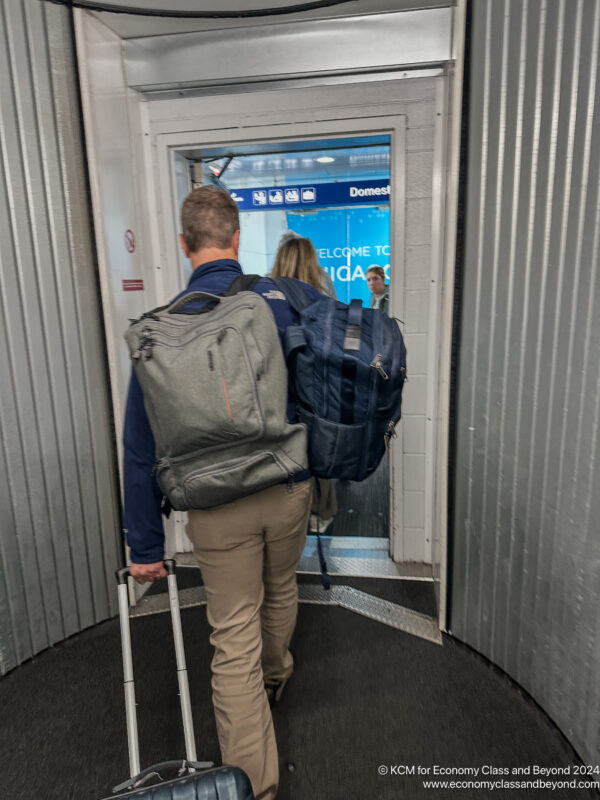 a man and woman with luggage walking through a doorway