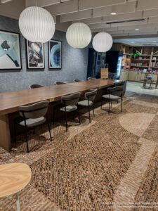 a long table with chairs in a room with a bookcase and pictures