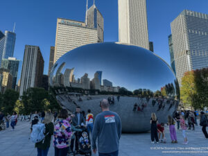 a group of people standing in front of a large reflective object with Millennium Park in the background