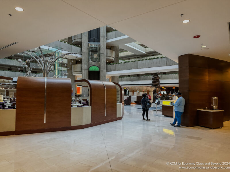 people inside a building with a glass wall and a tall ceiling