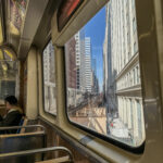 a window of a train with a woman sitting on a bench