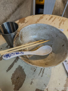 a bowl with chopsticks and a spoon on a table