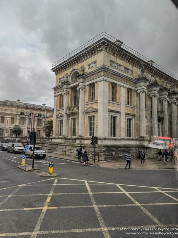 a building with columns and people walking on a street