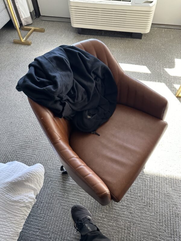 a brown chair with a black jacket on it