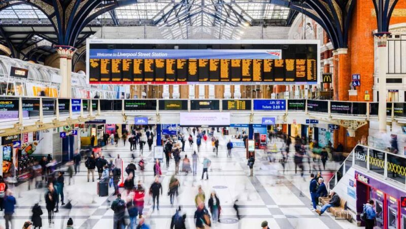 a group of people in a train station with Liverpool Street station in the background