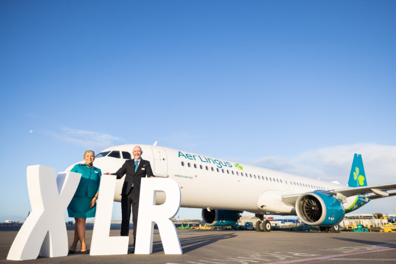 a man and woman standing in front of a large white and blue airplane