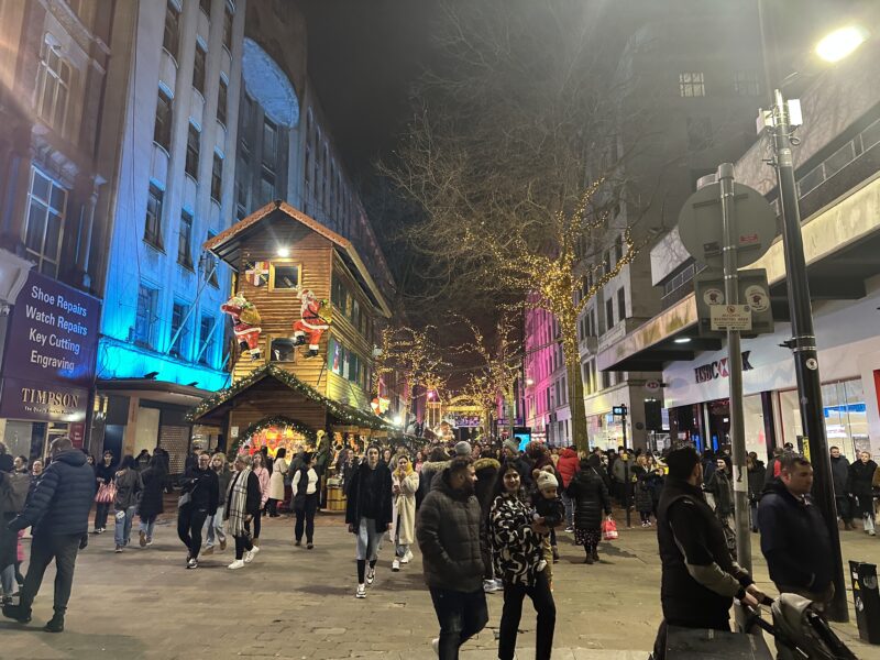 a crowd of people walking on a street with lights