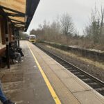 people sitting on a bench next to a train