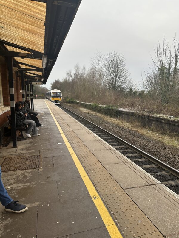 people sitting on a bench next to a train