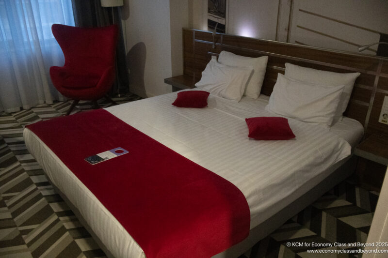 a bed with red blanket and pillows