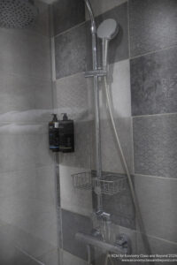 a shower with a shower head and soap dispenser