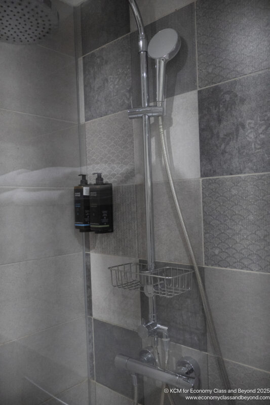 a shower with a shower head and soap dispenser