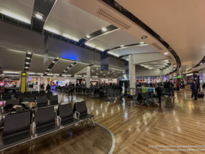 a large airport terminal with many chairs and people