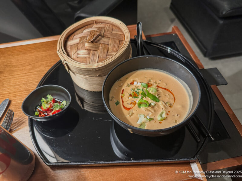 a bowl of soup and a container of food on a tray