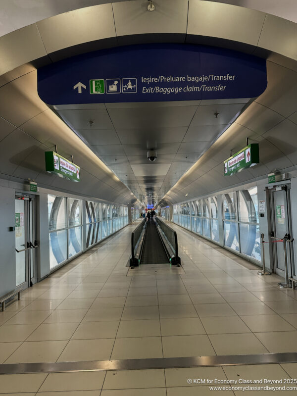 a walkway with signs and luggage carousels