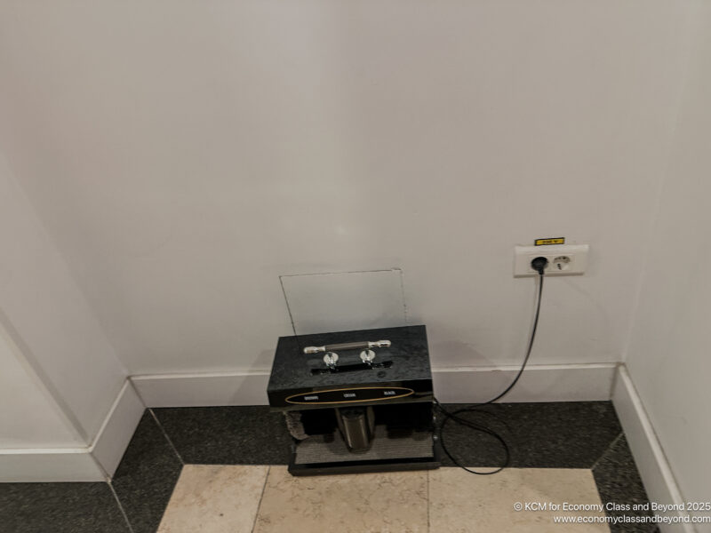 a black rectangular object with knobs and a cord plugged into a wall