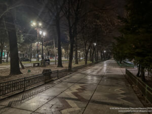 a sidewalk with trees and lights at night