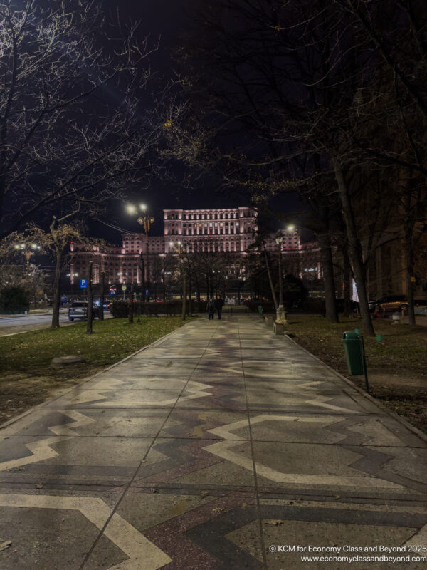 a walkway with trees and a building in the background