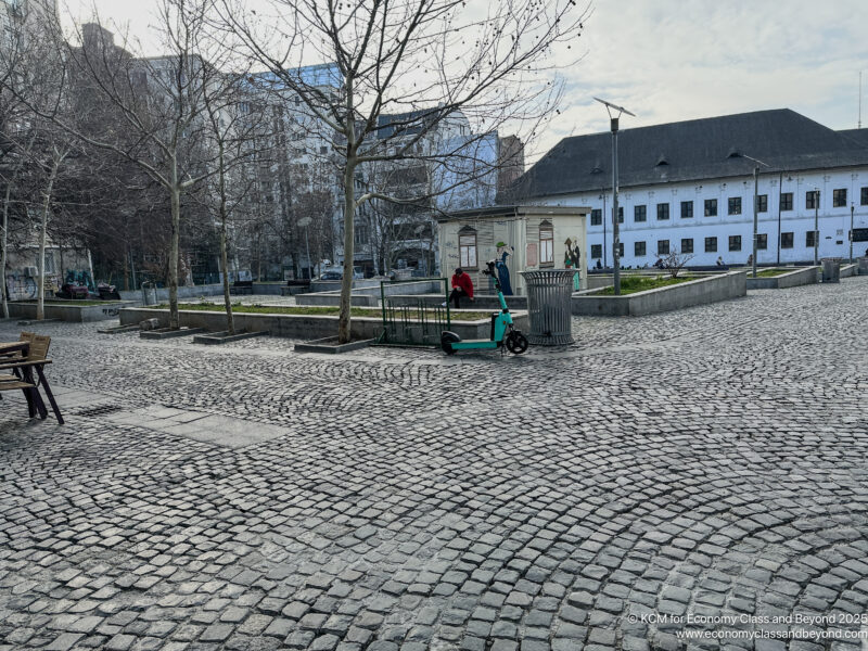 a stone paved area with trees and buildings