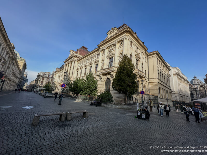 a stone building with trees and people walking around