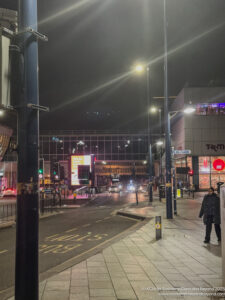 a street with lights and people walking on it