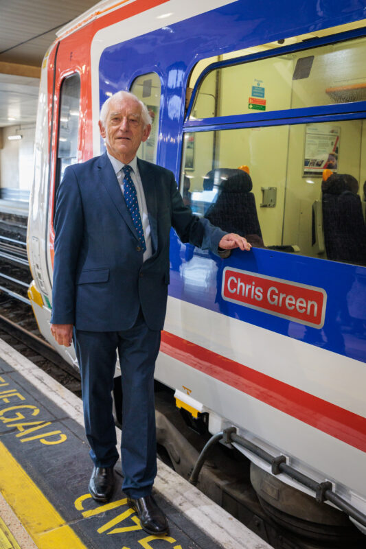 a man in a suit standing next to a train