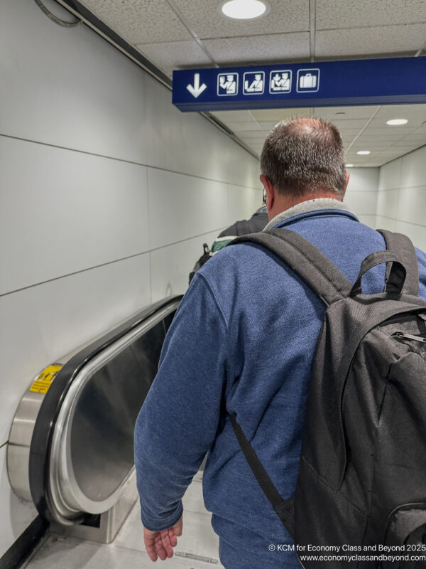 a man with a backpack walking down an escalator