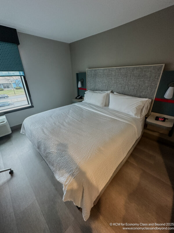 a bed with white sheets and pillows in a room
