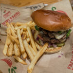 a burger and fries on a paper wrapper at Chilli's