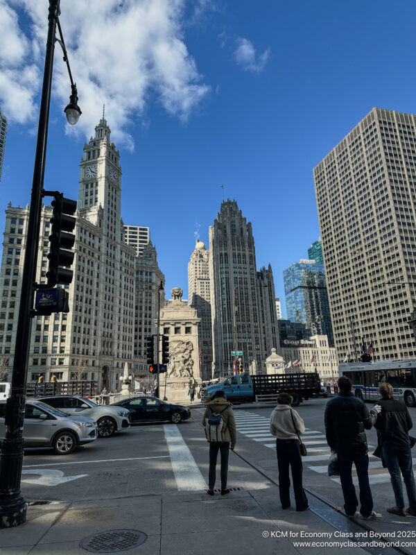 a group of people standing on a street with cars and buildings in the background