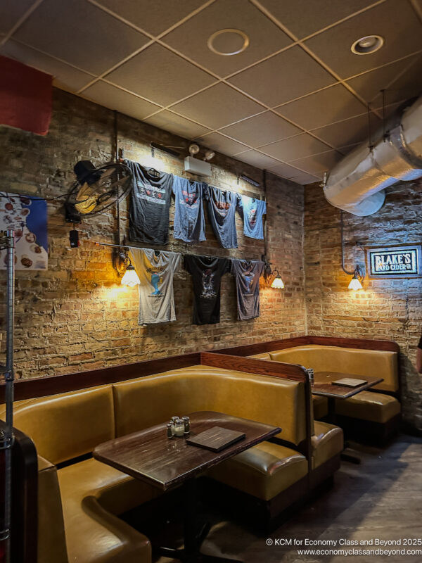 a room with booth seating and a table with a few t-shirts on the wall