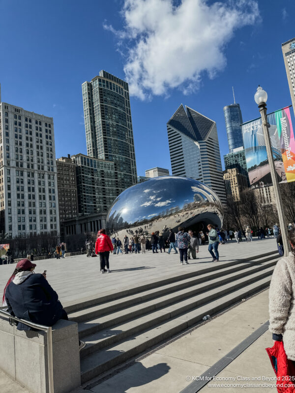a group of people walking around a large reflective object